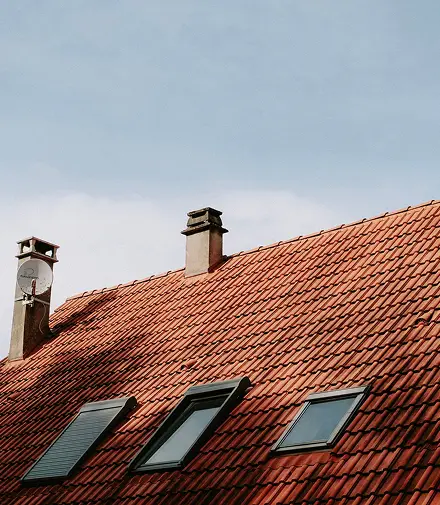Red tile roof with chimneys and skylights on a Colorado home