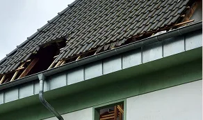 Roof with missing tiles exposing the roof deck, a common cause of roof leaks in Denver homes