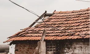Storm-damaged clay tile roof with broken and missing tiles